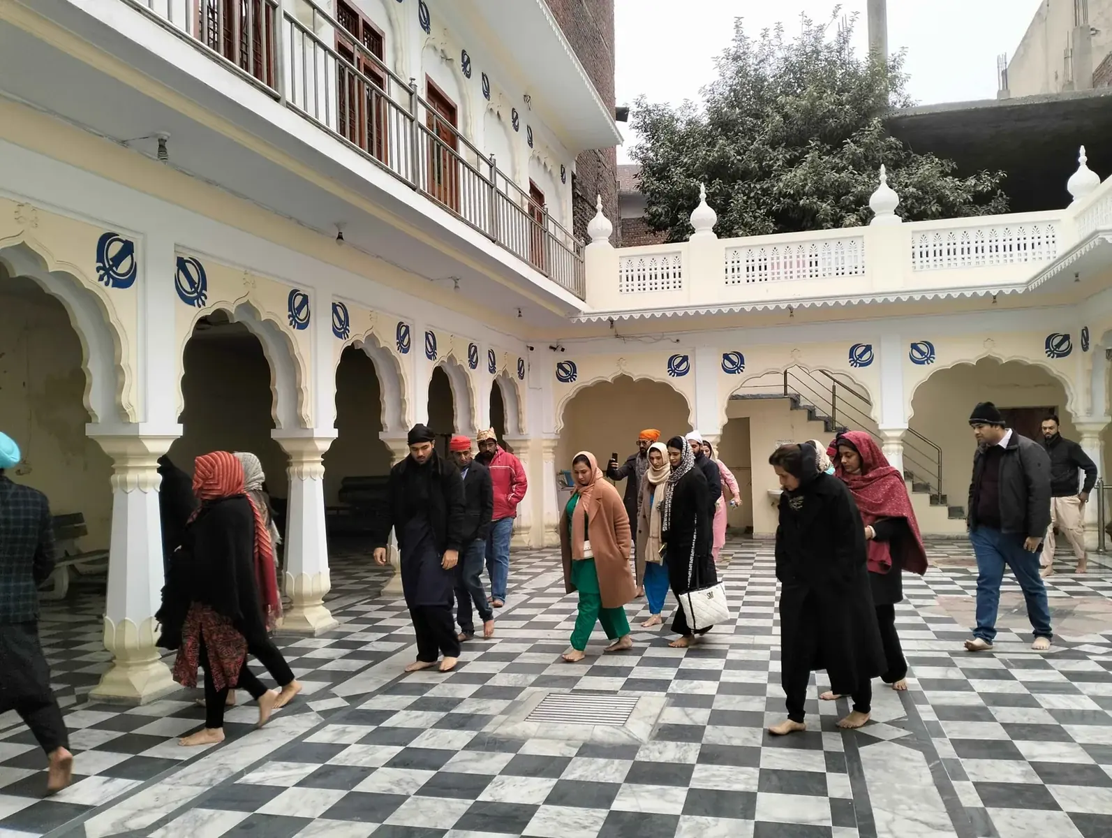 Visitors walking through a historic gurdwara courtyard in Lahore